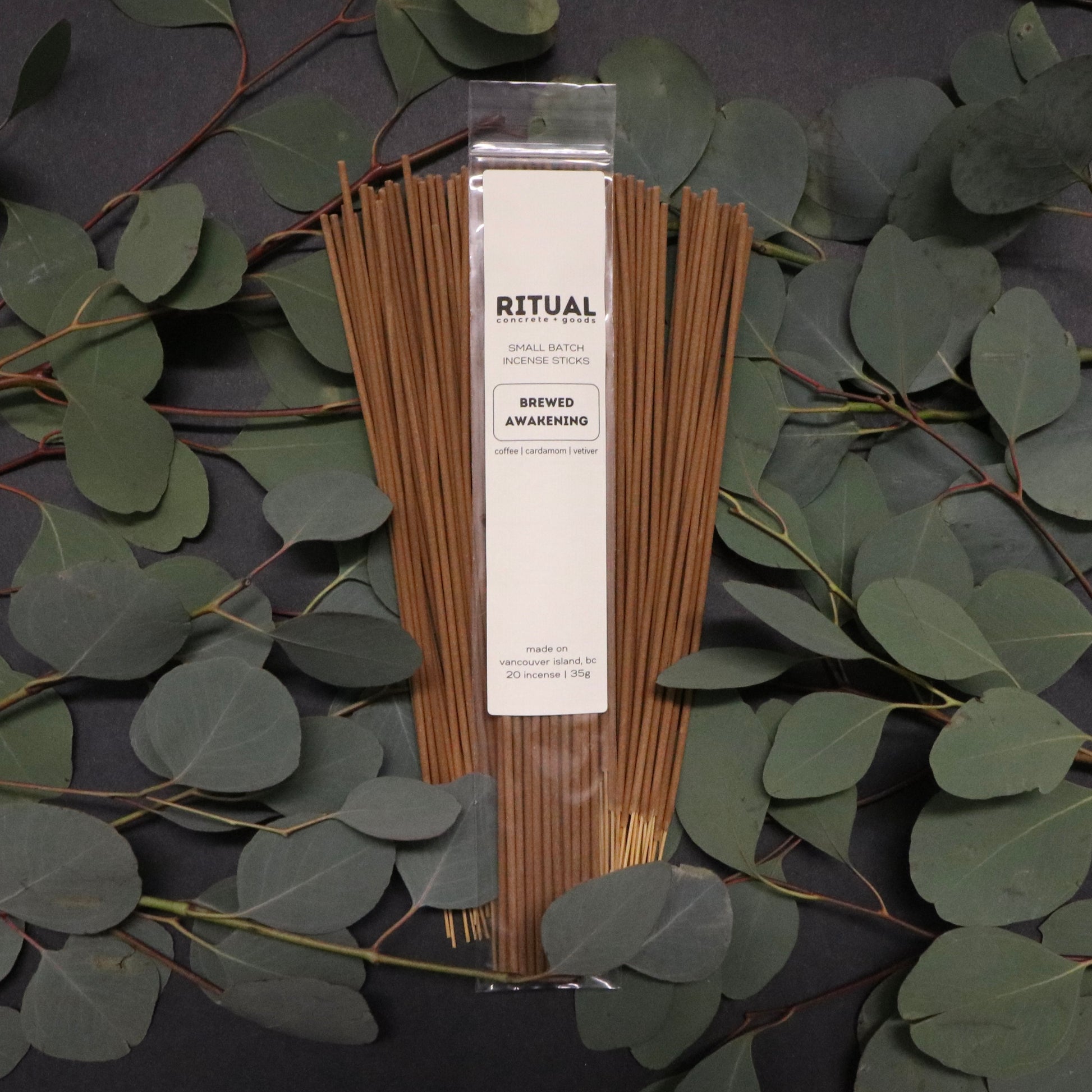Packaged incense sticks with a label on a dark background with eucalyptus leaves