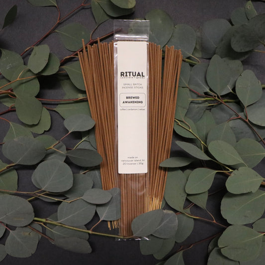 Packaged incense sticks with a label on a dark background with eucalyptus leaves