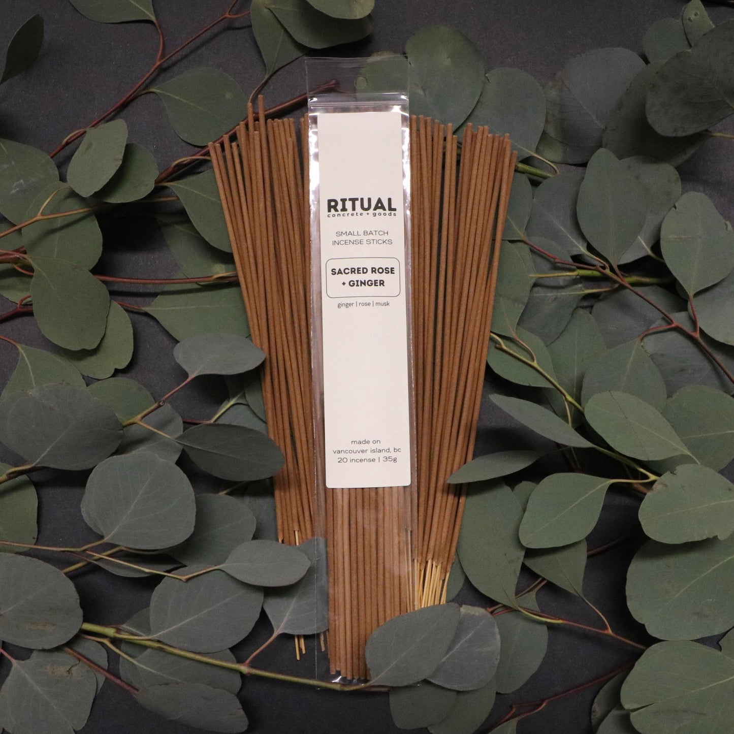 Packaged incense sticks with a label on a dark background with green leaves