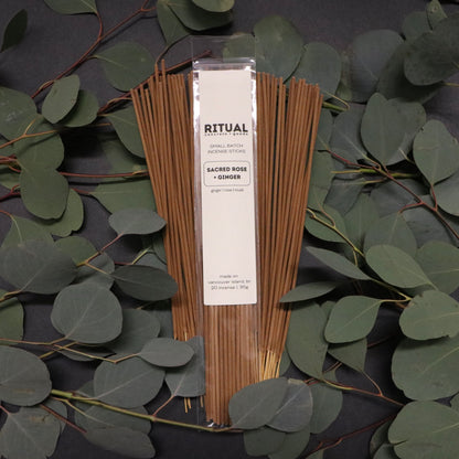 Packaged incense sticks with a label on a dark background with green leaves
