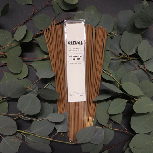 Packaged incense sticks with a label on a dark background with green leaves