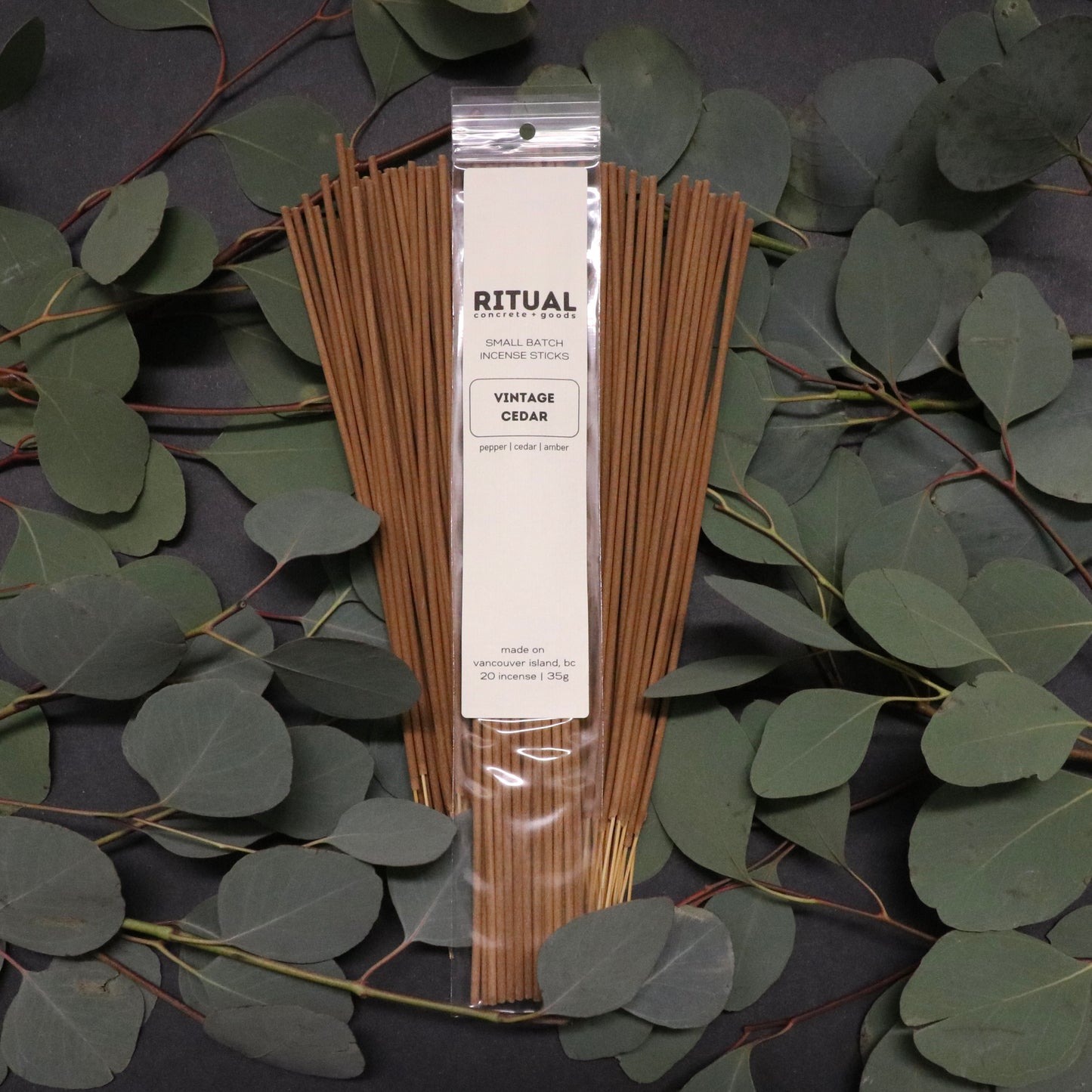Pack of incense sticks with a visible brand label on a dark background with green leaves.