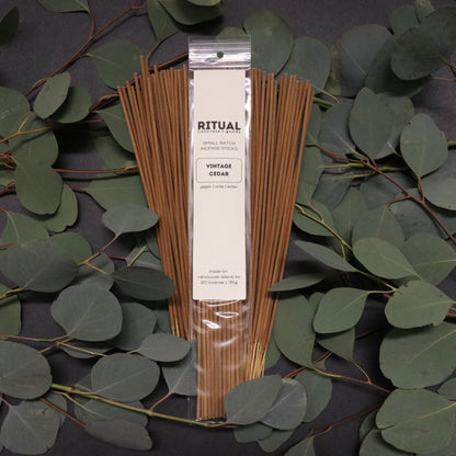 Pack of incense sticks with a visible brand label on a dark background with green leaves.